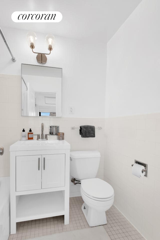 full bath with vanity, a wainscoted wall, tile patterned flooring, tile walls, and toilet