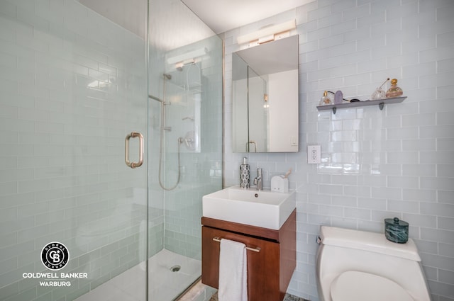 bathroom with tile walls, a stall shower, vanity, toilet, and decorative backsplash