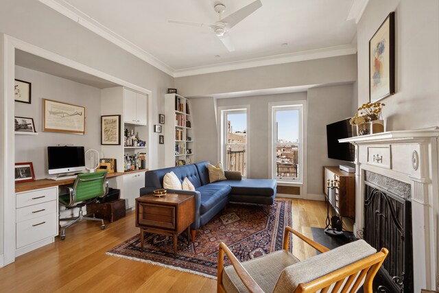 living room with ornamental molding, a ceiling fan, a high end fireplace, and light wood-style floors