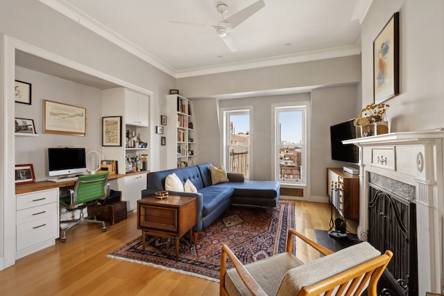 living room featuring ceiling fan, light wood-type flooring, crown molding, and a premium fireplace