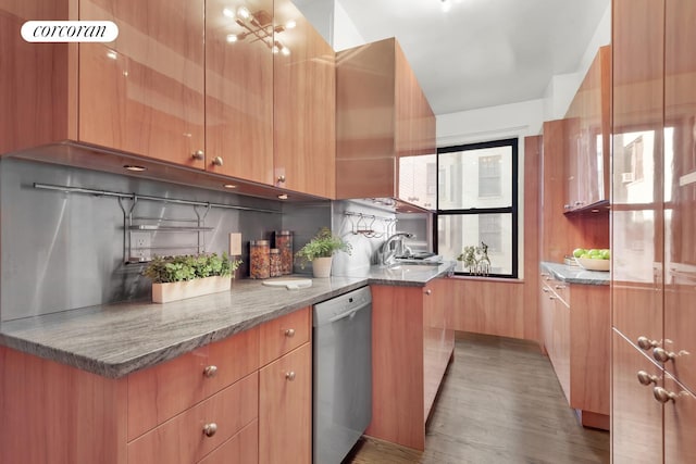 kitchen with modern cabinets, wood finished floors, stainless steel dishwasher, stone counters, and a sink