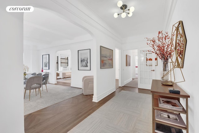 corridor featuring baseboards, visible vents, arched walkways, crown molding, and parquet flooring