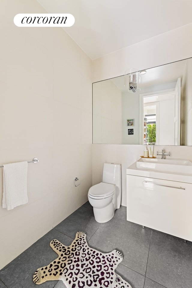 bathroom featuring vanity, tile walls, toilet, and tile patterned flooring