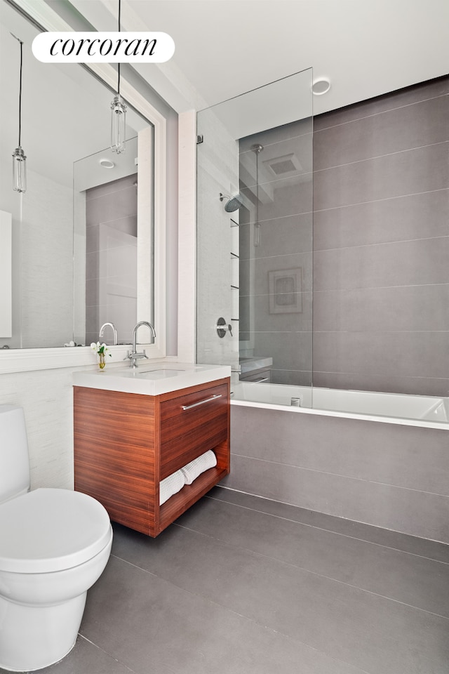 full bathroom featuring tiled shower / bath, toilet, vanity, and tile patterned flooring