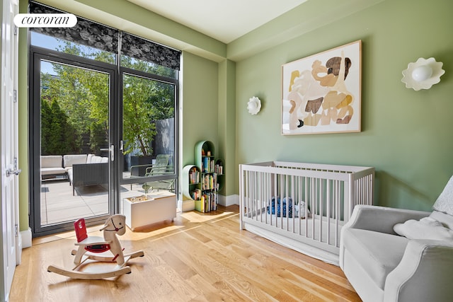 bedroom with a crib, baseboards, and wood finished floors