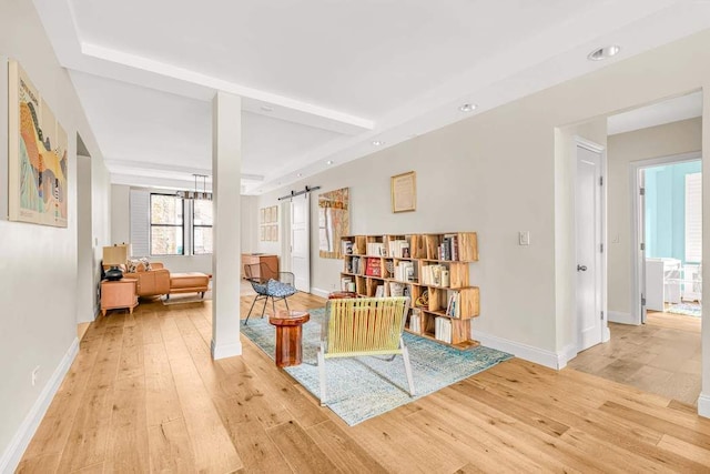 living area featuring a barn door, light wood-type flooring, and baseboards