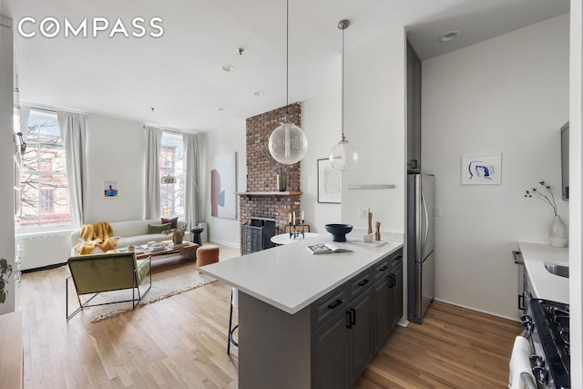 kitchen with light wood-style flooring, a peninsula, stainless steel appliances, and a breakfast bar area