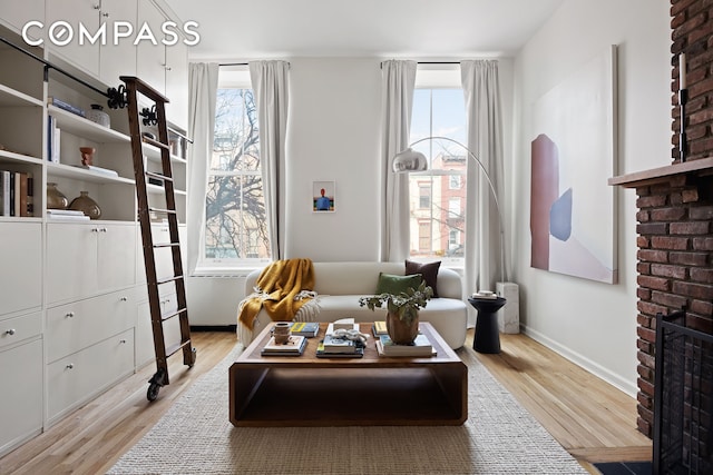 sitting room featuring a fireplace, baseboards, and wood finished floors