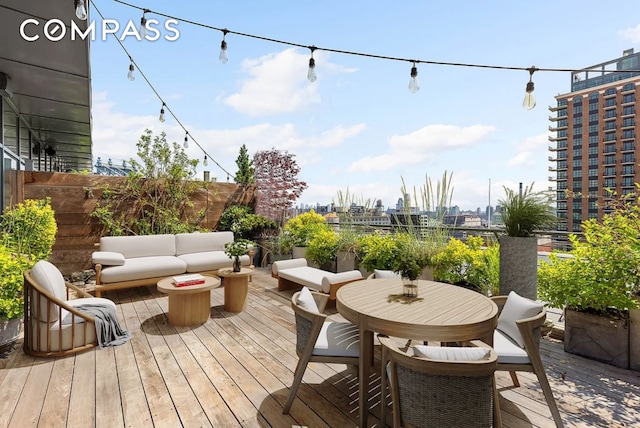 wooden deck featuring an outdoor hangout area, fence, and a city view