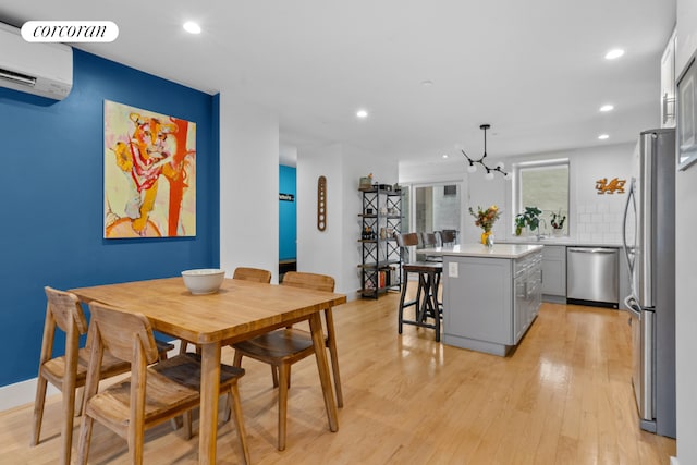 dining space with an AC wall unit, recessed lighting, and light wood-type flooring