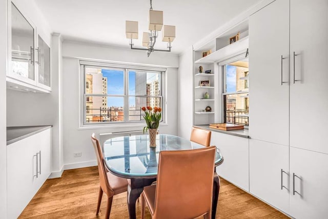 dining room with a chandelier, light wood-type flooring, and baseboards