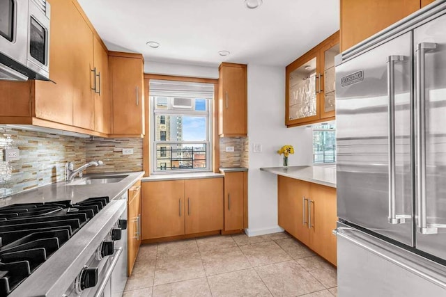 kitchen featuring light tile patterned floors, plenty of natural light, stainless steel appliances, and brown cabinetry