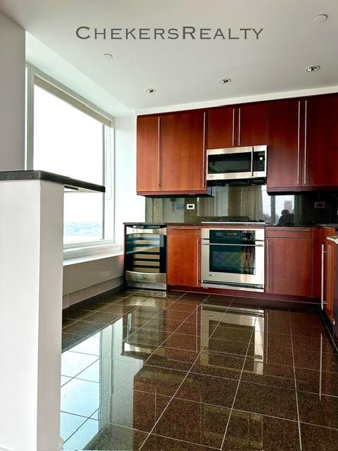 kitchen with granite finish floor, backsplash, beverage cooler, and stainless steel appliances