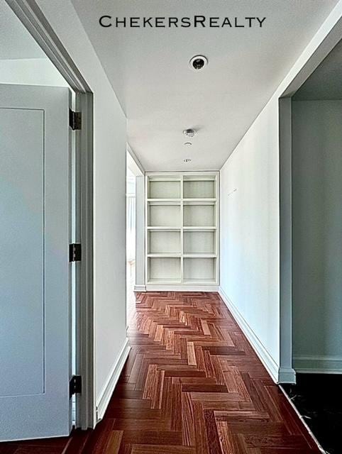 hallway with baseboards and built in shelves