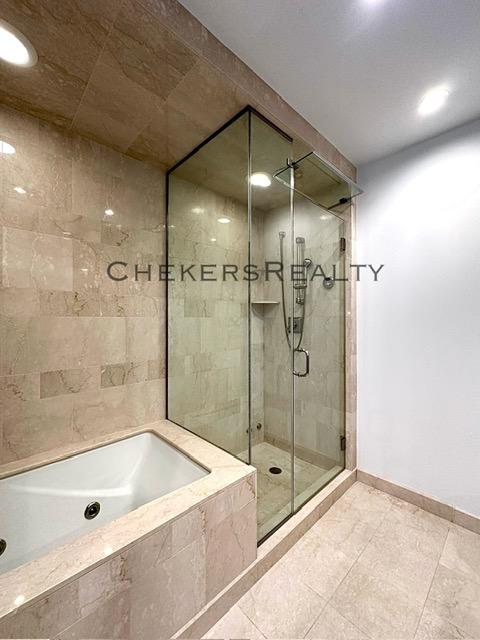 bathroom with a shower stall, a bath, baseboards, and tile patterned floors