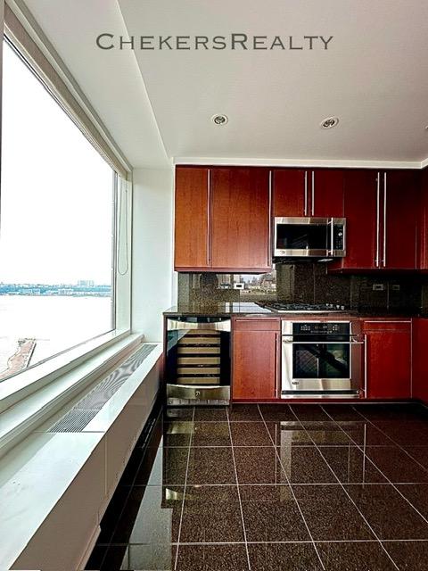 240 Riverside Blvd Unit 19-C, New York City, NY 10069 - kitchen with stainless steel appliances, granite tiled floors, wine cooler, dark countertops, and recessed lighting