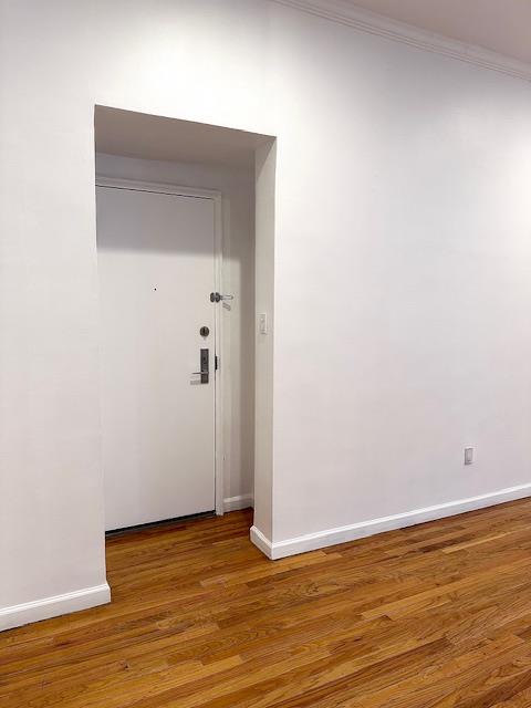 interior space with crown molding, wood finished floors, and baseboards