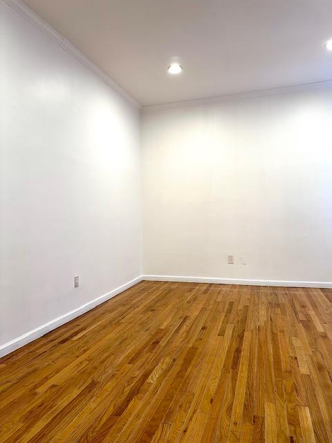 spare room featuring crown molding, baseboards, and wood finished floors