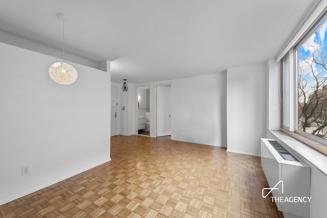 spare room with radiator, plenty of natural light, and baseboards