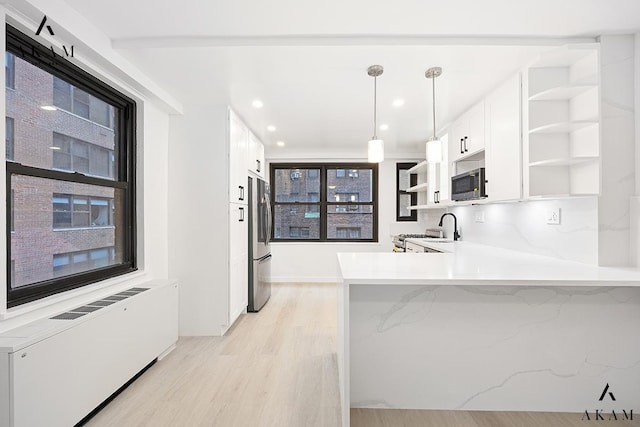 kitchen with open shelves, stainless steel appliances, radiator, light wood-style floors, and white cabinetry