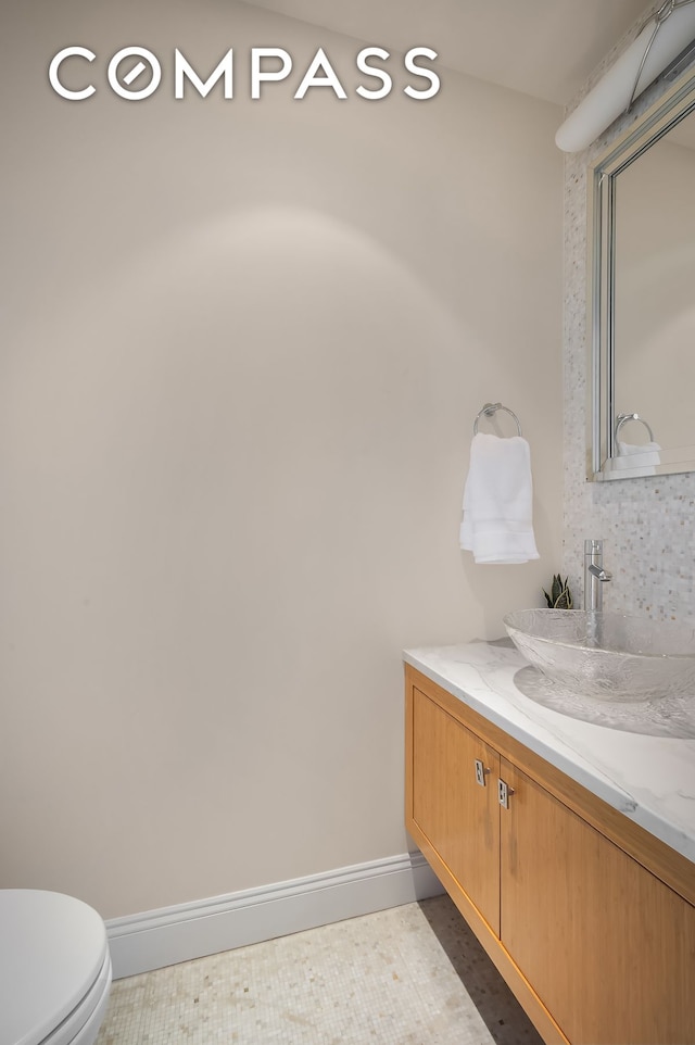 bathroom featuring toilet, vanity, and baseboards