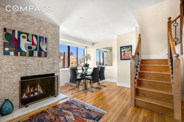 office space featuring light wood-style floors, baseboards, a large fireplace, and a city view