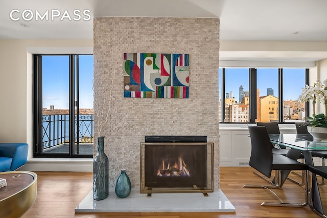 living room with a warm lit fireplace, light wood-type flooring, and a city view