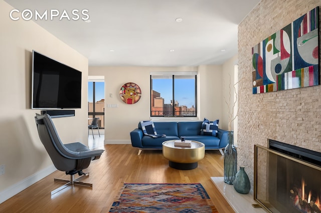 living room with a lit fireplace, baseboards, and wood finished floors