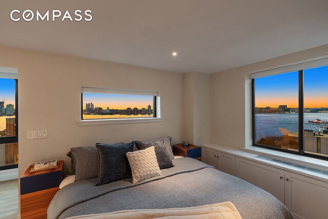 bedroom with recessed lighting, wood finished floors, and a city view