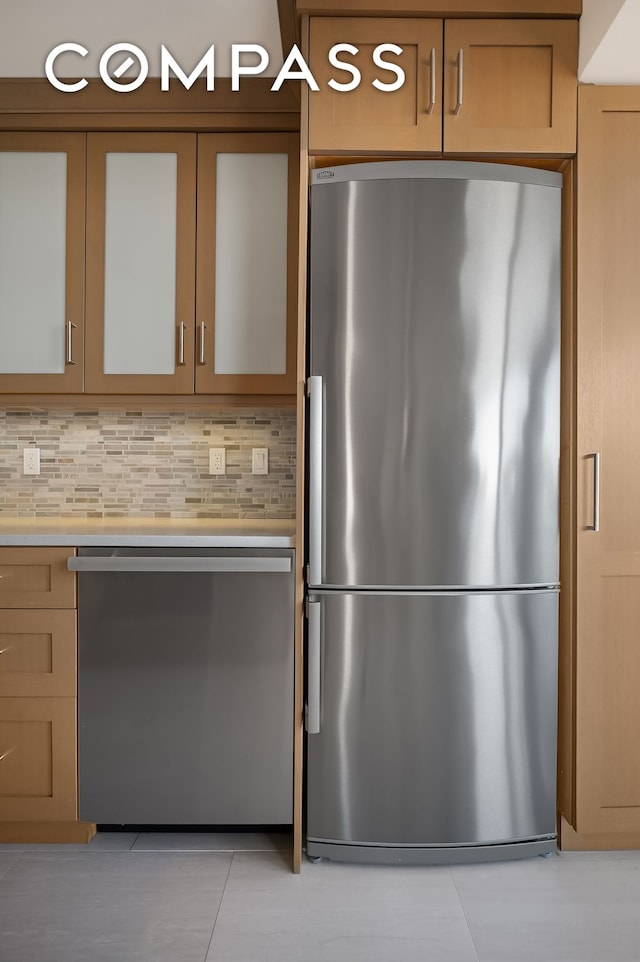 kitchen with light tile patterned floors, stainless steel appliances, light countertops, and decorative backsplash