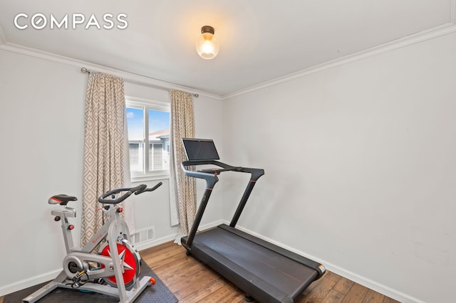 exercise area featuring visible vents, wood finished floors, baseboards, and ornamental molding