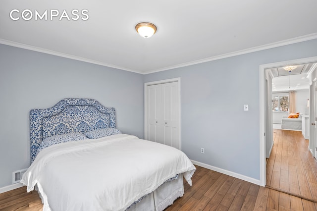 bedroom with visible vents, baseboards, attic access, ornamental molding, and wood-type flooring