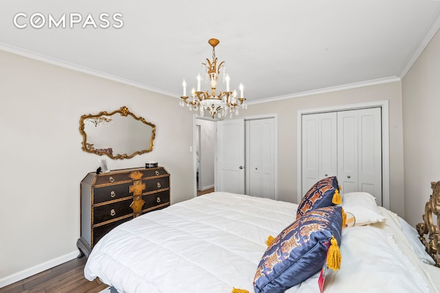 bedroom featuring a notable chandelier, two closets, ornamental molding, dark wood finished floors, and baseboards