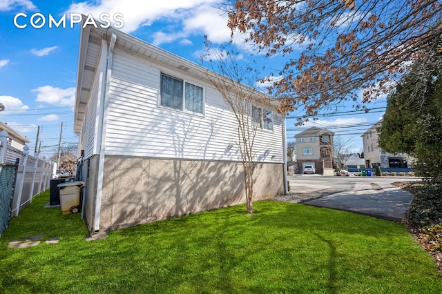 view of side of property featuring a lawn and fence