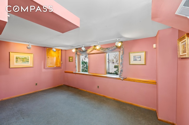 empty room with track lighting, carpet, and baseboards