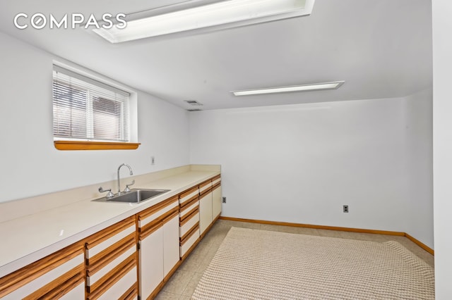 kitchen featuring light countertops, visible vents, baseboards, and a sink