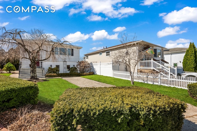 back of house featuring a fenced front yard and a lawn