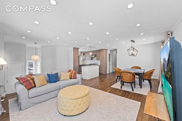 living room with dark wood finished floors, crown molding, and recessed lighting