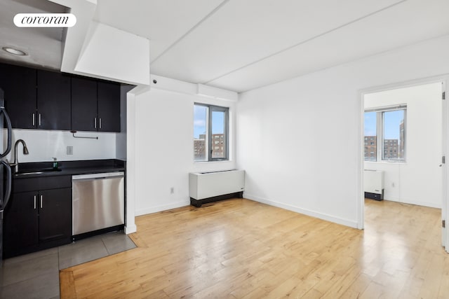 kitchen with dishwasher, dark countertops, radiator heating unit, dark cabinetry, and light wood-style floors