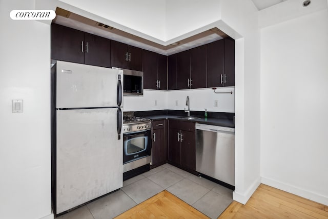 kitchen with visible vents, dark countertops, appliances with stainless steel finishes, dark brown cabinets, and a sink