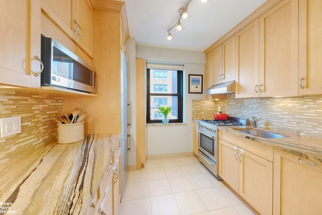 kitchen with light stone counters, light brown cabinets, under cabinet range hood, stainless steel appliances, and a sink