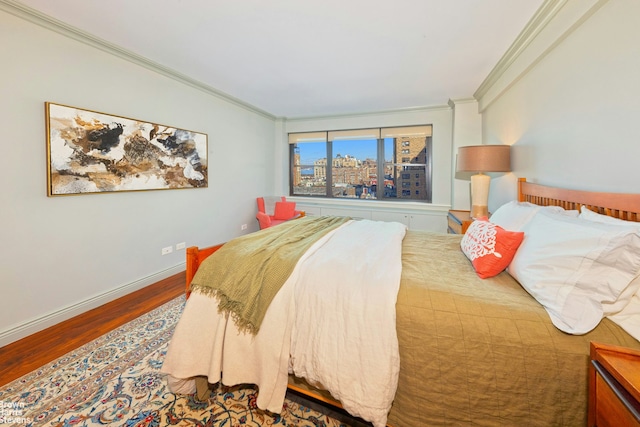 bedroom with a city view, crown molding, baseboards, and wood finished floors