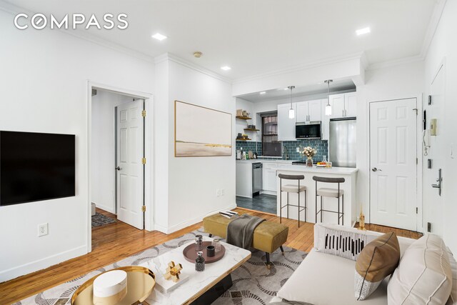 living area with ornamental molding, recessed lighting, baseboards, and wood finished floors