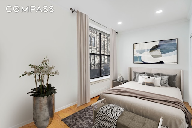 bedroom with baseboards, ornamental molding, and light wood finished floors