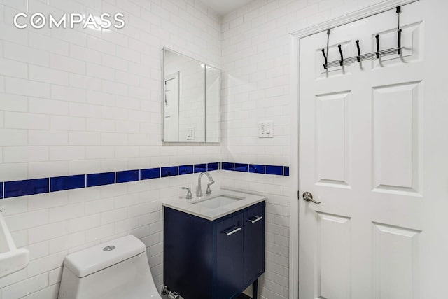bathroom with vanity, toilet, and tile walls