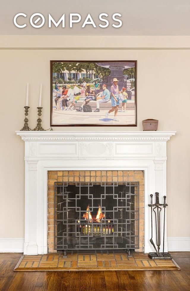 interior details with baseboards, a lit fireplace, and wood finished floors