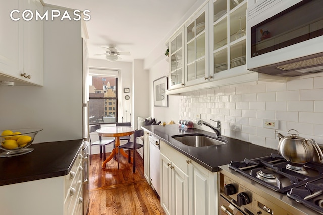 kitchen with white microwave, dark countertops, dark wood finished floors, a ceiling fan, and a sink