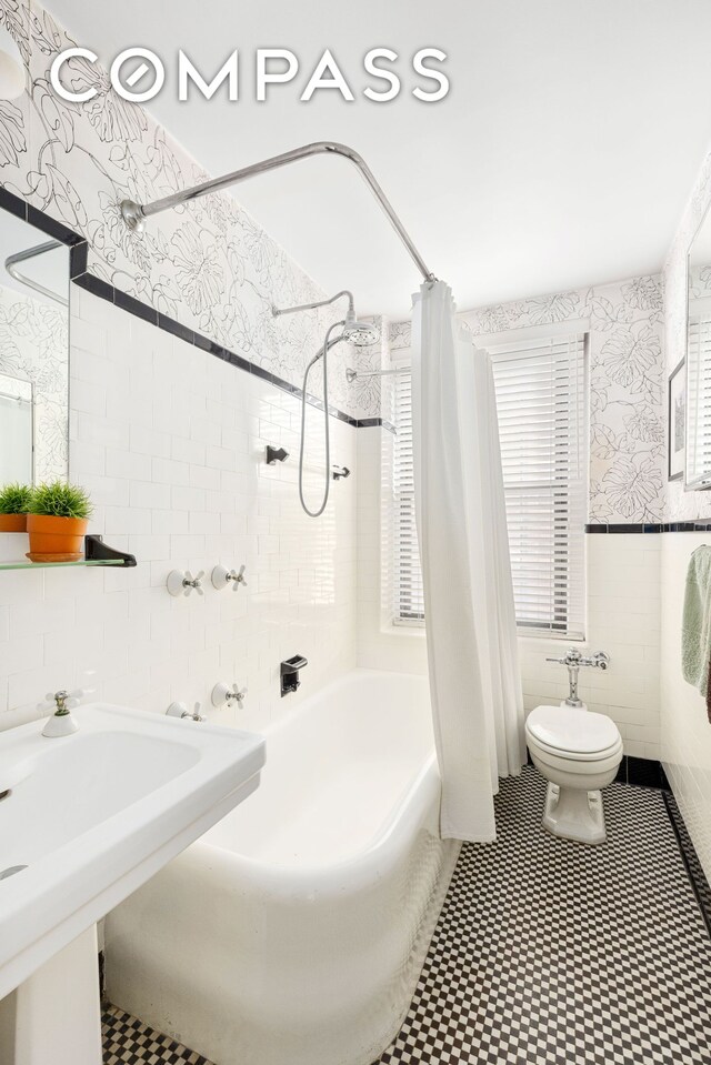 205 E 78th St Unit 9F, New York City, NY 10075 - full bath featuring tile walls, wallpapered walls, toilet, shower / tub combo, and a sink