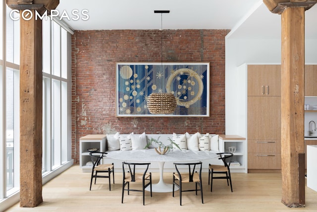 interior space with breakfast area, wood finished floors, and brick wall