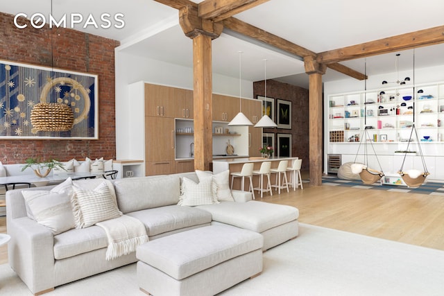 living room featuring beamed ceiling, wood finished floors, and brick wall